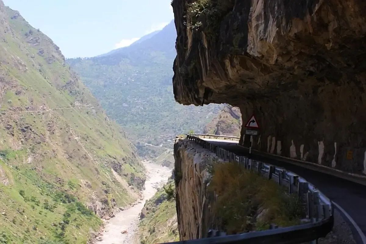 The Kinnaur road cut into an overhanging cliff on the way to Spiti, guardrail on the outside and the river in the gorge below.