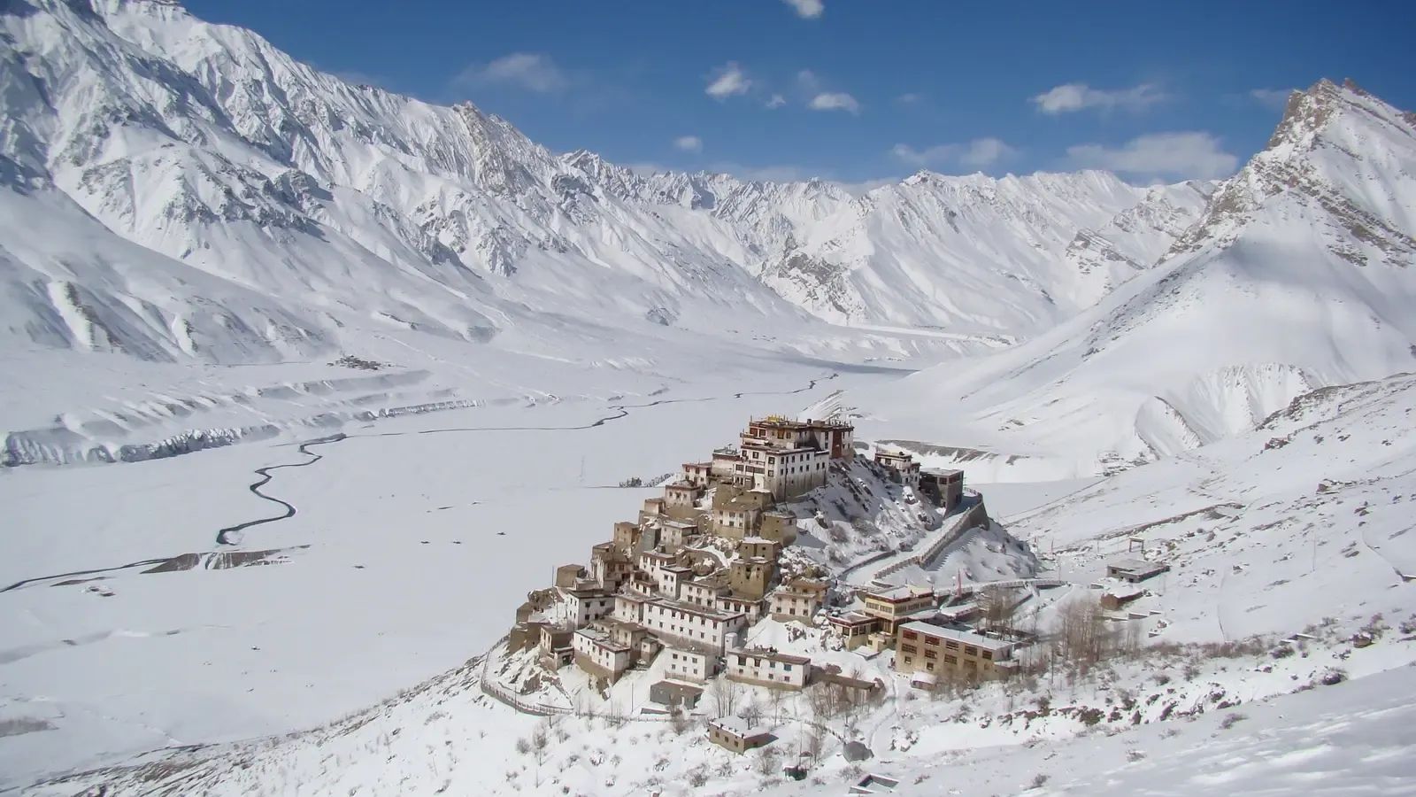 Key monastery stacked up its own hill in deep winter snow, the frozen river winding away down a white valley behind it.