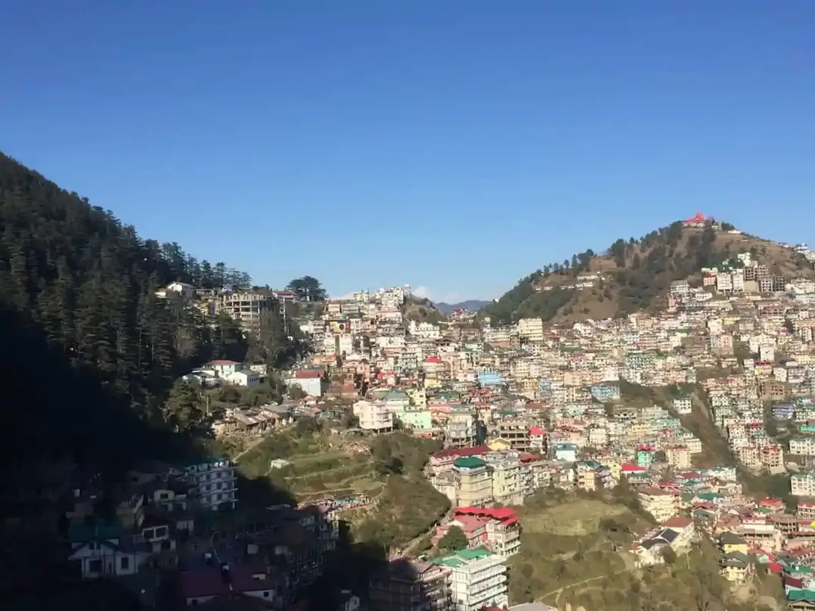 A hill town stacked steeply up its slope, roofs and terraces packed together under heavy cloud.